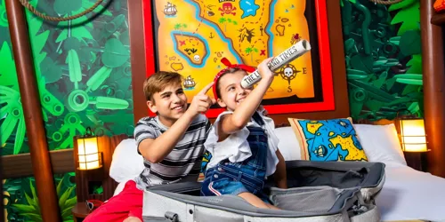 Two kids look through a monocular in a pirate-themed hotel room